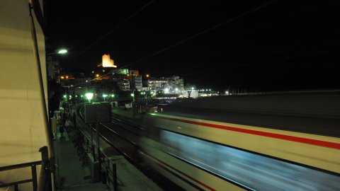 El tren arriba a Sant Pol de Mar, amb l'ermita de Sant Pau il·luminada al fons. 7 d'agost de 2010