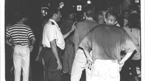 Un agent de la Policia Local de Calella demana silenci als turistes a la sortida de les discoteques de la població en plena temporada turística. Calella. 1991. Foto: Saül Gordillo (El Punt)