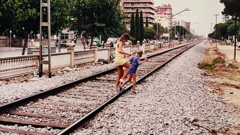Una turista i la seva filla creuen la via del tren a Malgrat de Mar. Revista Repòrter de l'Alt Maresme. Anys 90. Foto: Saül Gordillo (Repòrter)
