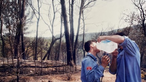 Els bombers es refresquen en l'extinció d'un incendi a prop d'Hortsavinyà, entre els termes municipals de Calella i Tordera. Revista Repòrter de l'Alt Maresme. Anys 90. Foto: Saül Gordillo (Repòrter)