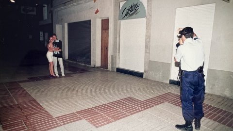La Policia Local de Calella patrulla una nit d'estiu i uns turistes li demanen a un agent que els hi faci una fotografia. Revista Repòrter de l'Alt Maresme. Anys 90. Foto: Saül Gordillo (Repòrter)