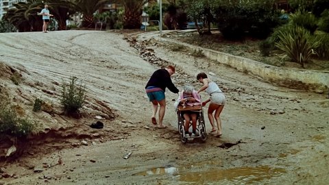 Turistes creuant la riera Capaspre de Calella un dia de pluja quan encara no s'havia fet la canalització i cobriment. Calella. Anys noranta. Foto: Saül Gordillo (El Punt / Repòrter)