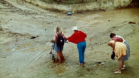 Turistes creuant la riera Capaspre de Calella un dia de pluja quan encara no s'havia fet la canalització i cobriment. Calella. Anys noranta. Foto: Saül Gordillo (El Punt / Repòrter)