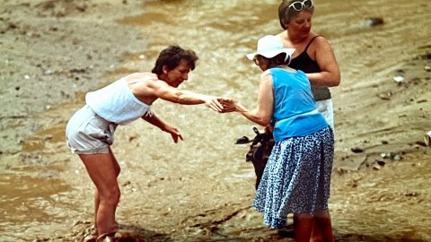 Turistes creuant la riera Capaspre de Calella un dia de pluja quan encara no s'havia fet la canalització i cobriment. Calella. Anys noranta. Foto: Saül Gordillo (El Punt / Repòrter)