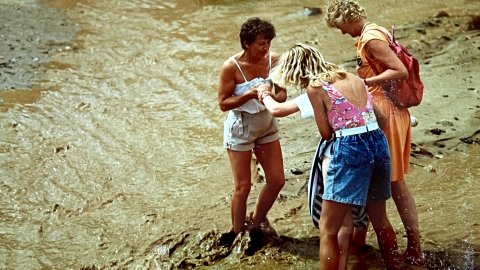 Turistes creuant la riera Capaspre de Calella un dia de pluja quan encara no s'havia fet la canalització i cobriment. Calella. Anys noranta. Foto: Saül Gordillo (El Punt / Repòrter)
