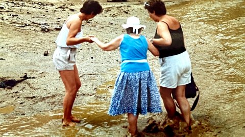 Turistes creuant la riera Capaspre de Calella un dia de pluja quan encara no s'havia fet la canalització i cobriment. Calella. Anys noranta. Foto: Saül Gordillo (El Punt / Repòrter)