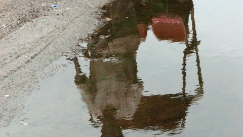 Taxi-bicicleta a Delhi, reflectit en una bassa. Agost de 2007