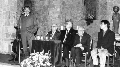El filòleg i lingüista Joan Coromines a l'ermita de Sant Pau de Sant Pol de Mar, en l'acte d'homenatge al seu pare, Pere Coromines. Al seu costat, l'expresident del Parlament Heribert Barrera i el llavors alcalde de Sant Pol, Francesc Pomés, mentre intervé l'historiador Josep Maria Ainaud de Lasarte. Sant Pol de Mar. 25 de gener de 1992 